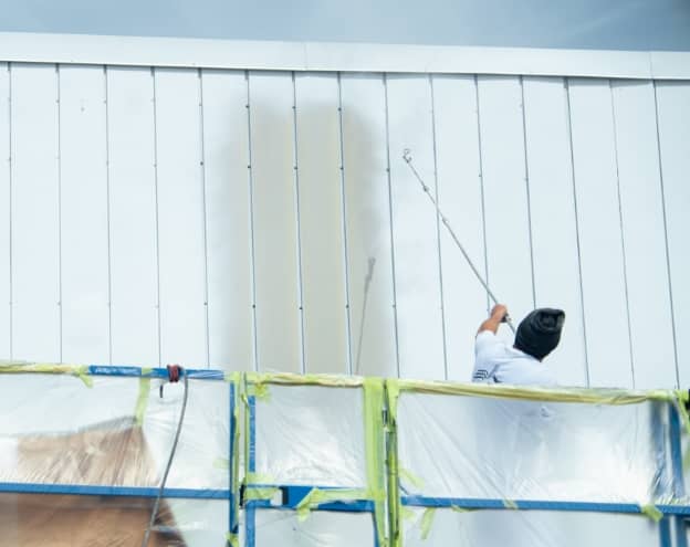 un homme travaillant sur la peinture extérieure d'un entrepôt